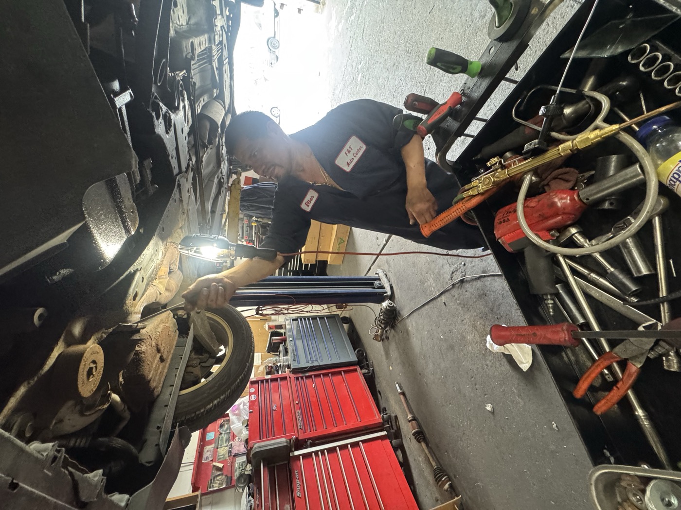 Mechanic working on wheel hub and suspension under a lifted car